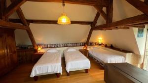 two beds in a room with a ceiling with beams at Gîte Hurlevent in Azay-le-Rideau