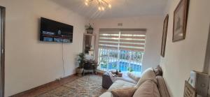 a living room with a couch and a large window at Saint Blaize Cottage in Boksburg