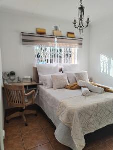 a bedroom with a bed and a desk and a window at Saint Blaize Cottage in Boksburg
