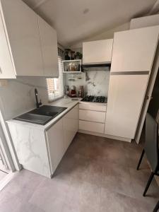 a kitchen with white cabinets and a sink at FLAMANTS ROSES 2 in Frontignan