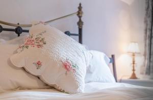 a pillow sitting on top of a bed at Beautiful chocolate box thatched cottage in heart of Lustleigh, 1 min walk to pub, tearoom & shop in Lustleigh +19 photos
