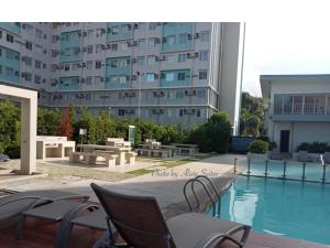 a swimming pool with chairs and a large building at Aliste Suites Marina Spatial in Dumaguete