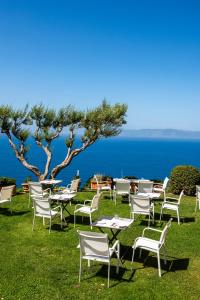 a group of chairs and tables on the grass near the ocean at Boutique Hotel Torre Di Cala Piccola in Porto Santo Stefano