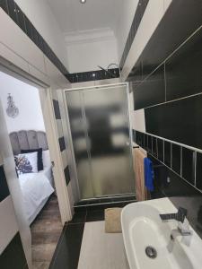 a bathroom with a sink and a shower and a bed at Thee Agolo Guesthouse in Vryburg