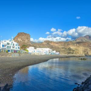 a view of a beach with white buildings and mountains at La Avenida Las Nieves Agaete in Puerto de las Nieves