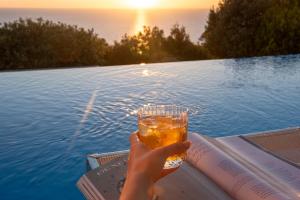 a person holding a glass of beer next to a pool at Boutique Hotel Torre Di Cala Piccola in Porto Santo Stefano