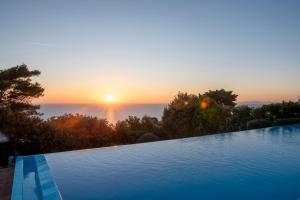 a swimming pool with a sunset in the background at Boutique Hotel Torre Di Cala Piccola in Porto Santo Stefano
