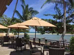 a restaurant with chairs and umbrellas on the beach at Maehaad Bay Resort - SHA Plus in Mae Haad