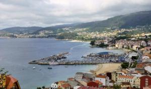 a city with a harbor and a beach with boats at Apartamento Ons in Bueu +8 photos