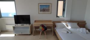 a bedroom with two beds and a desk with a television at Endless Blue - Rafina Seaview Apartment in Rafina