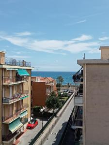 un'auto rossa è parcheggiata su una strada accanto agli edifici di Vista Mare a 150 mt dalla spiaggia - free parking e AC a Pietra Ligure