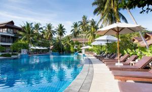 a pool at a resort with chairs and umbrellas at Maehaad Bay Resort - SHA Plus in Mae Haad