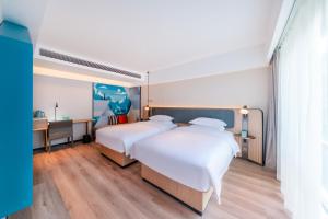 a hotel room with two beds and a desk at Echarm Hotel - Kunming Station South Asia Style Street Branch in Kunming