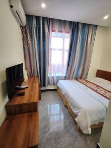 una camera da letto con un letto, una scrivania e una televisione di Harbin Qiju Hotel Taiping International Airport a Wujia
