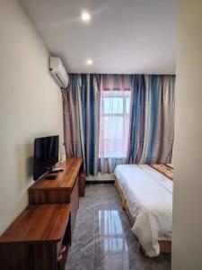 una camera d'albergo con un letto e una televisione di Harbin Qiju Hotel Taiping International Airport a Wujia