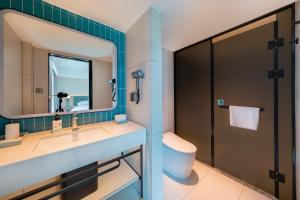 a bathroom with a sink and a toilet and a mirror at Echarm Hotel - Kunming Station South Asia Style Street Branch in Kunming