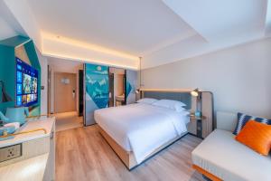 a bedroom with a large white bed and a couch at Echarm Hotel - Kunming Station South Asia Style Street Branch in Kunming