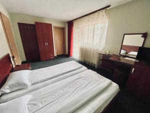 a bedroom with a bed and a desk and a mirror at Pensiunea BUJOR DE MUNTE in Voineasa +10 photos