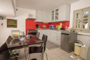 a kitchen with red and white cabinets and a table at Kiter's paradise beach house in Pounda