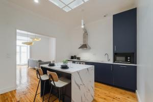 une cuisine avec des placards bleus et un îlot de cuisine avec des chaises dans l'établissement Setubal Terrace apartments, à Setúbal