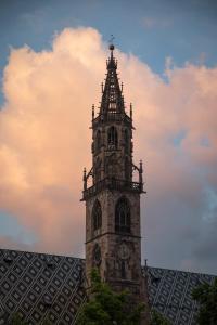 a tall tower with a clock on top of a building at Hotel Magdalener Hof in Bolzano