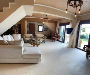 a large living room with white furniture and a staircase at Villa Sunset Siviri in Siviri