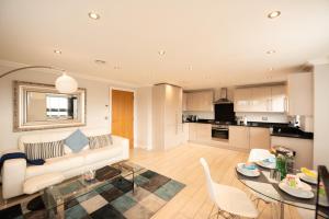 Una sala de estar con un sofá y una mesa con sillas. en Malthouse Court, en Reading