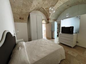 1 dormitorio con cama y vestidor con TV en Egnazia Short Holidays, en Fasano