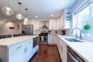 een keuken met witte kasten en roestvrijstalen apparaten bij Stylish 3BR w Pool Table & Garage in Philadelphia