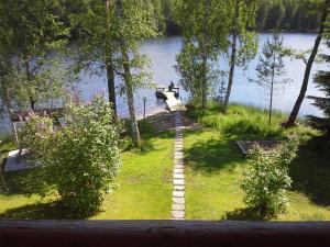 a path leading into a lake with a person sitting on a dock at Menninkäinen Cottage in Rutalahti