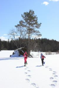 dwoje ludzi przechodzi przez śnieg z odciskami stóp w obiekcie Menninkäinen Cottage w mieście Rutalahti
