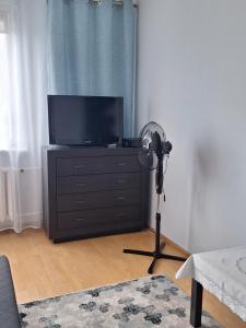 a room with a flat screen tv and a fan at Turkusowa Apartament in Szczecin