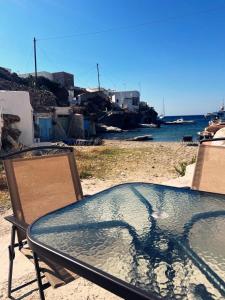 a glass table on a beach next to the water at Kimolos Seafront in Kimolos +2 photos