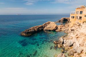 an old building on a cliff next to the ocean at Nina in Siġġiewi