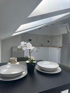 een zwarte tafel met witte borden en kopjes en een bloem bij Apartment Roni in Zadar
