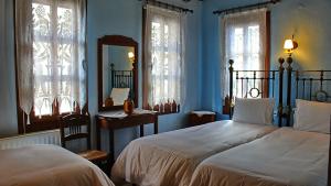 a blue bedroom with two beds and a mirror at Varosi Guesthouse in Edessa