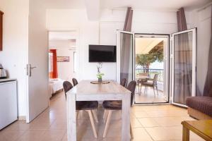 a dining room with a table with chairs and a television at Romanos Beach Villas in Romanu
