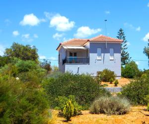 a white house with a balcony in the desert at Romanos Beach Villas in Romanu