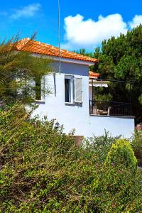 a white house on a hill with trees at Romanos Beach Villas in Romanu