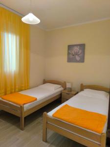 two beds in a room with yellow curtains at Apartment Marea in Tivat