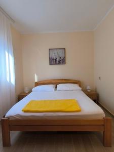 a bedroom with a bed with a yellow blanket on it at Apartment Marea in Tivat +1 photo