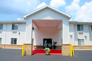 a white church with a red and white building at Budget Host Inn in Allegan