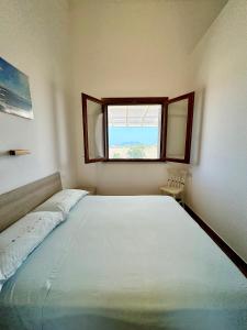 a bedroom with a large bed and a window at Aria case vacanze - Orzo in Favignana