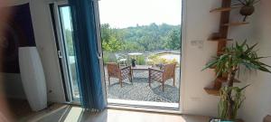 an open door to a patio with a table and chairs at le chemin de la nature in Équemauville +5 photos