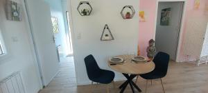 a dining room with a wooden table and blue chairs at le chemin de la nature in Équemauville