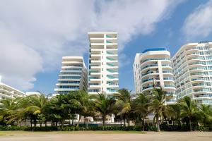 trois grands bâtiments blancs avec des palmiers au premier plan dans l'établissement 2 Dormitorios Morros. Vista Mar y salida playa, à Carthagène des Indes