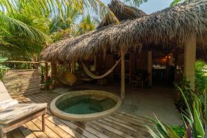 Un complejo turístico con jacuzzi y una cabaña con techo de paja. en Cabanas Adobe Frente Al Mar, en Puerto Escondido