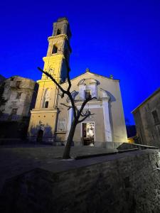 a church with a tower with a tree in front of it at Maison de village in Silvareccio
