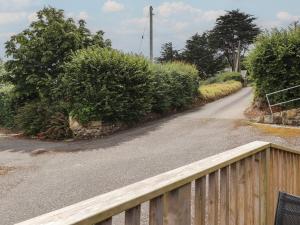 a road with a wooden fence and bushes on it at The Grain Store in Abersoch
