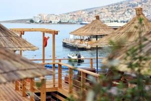 un molo con ombrelloni e una barca in acqua di Golden Beach Suites a Sarandë